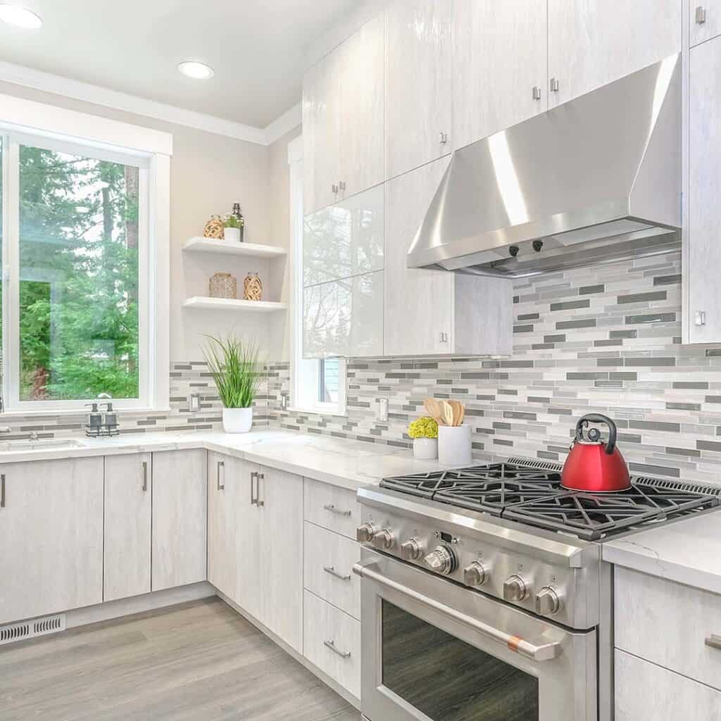 A nice, large kitchen space with white granite countertops and cabinets.